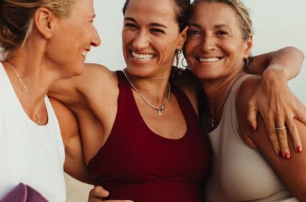 3 women in sportswear embracing each other and smiling